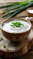 A bowl of tasty sour cream adorned with fresh green chives close-up. Inviting creamy cream on the scene that awakens your appetite in a delicious dish.