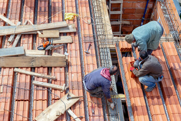 Construction workers prepare a steel mesh to reinforce a roof slab extension before pouring a...