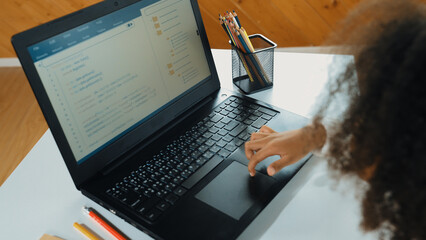 African girl moving touch pad while using laptop programing code and writing prompt code in STEM education. Children learning to designing setting engineering prompt at school. Top view. Erudition.