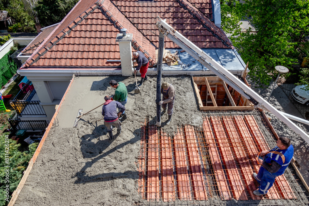 Wall mural construction workers pour concrete mix on a steel reinforced roof slab.