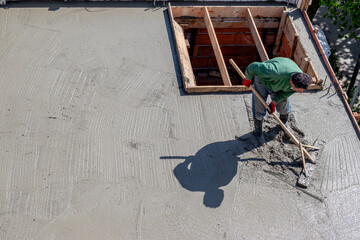 Construction worker leveling concrete on a roof slab.