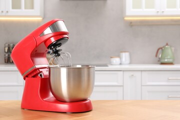 Modern red stand mixer on wooden table in kitchen, space for text