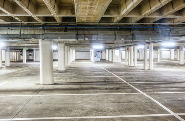 empty paid underground car parking, concrete poles artificial cool neon lights standard bay size