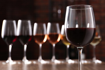 Different tasty wines in glasses against blurred background