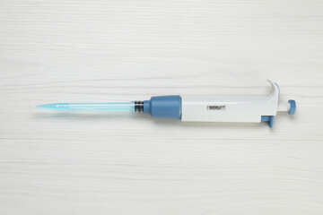Laboratory analysis. Micropipette with liquid on white wooden table, top view
