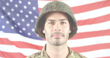Obraz premium Caucasian male soldier wearing camouflage stands before American flag