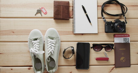 Travel essentials laid out on wooden surface, including shoes and a camera