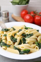 Tasty pasta with spinach on grey table, closeup