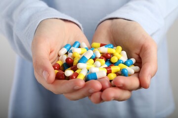 Woman holding many antibiotic pills, closeup. Medicinal treatment