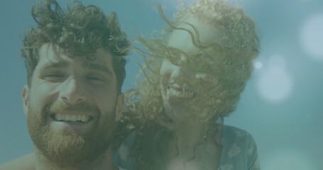Caucasian couple are smiling underwater, both have curly hair