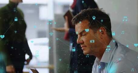 Image of icons connected with lines over caucasian man scrolling on smartphone in office