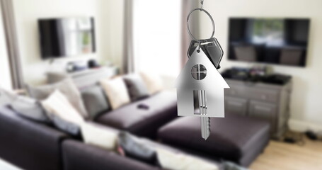 Silver house keys hanging against interior of modern living room in background
