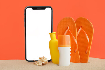 Bottles of sunscreen cream with flip-flops on sand against color background
