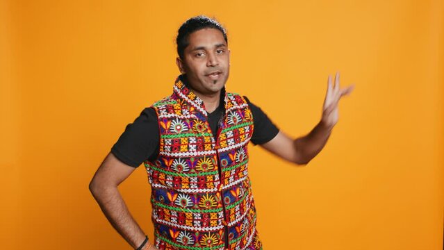 Joyful person having fun, dancing on rhythm, enjoying days off from work. Upbeat indian man entertaining himself doing funky movements, swinging arms, studio background, camera B