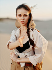 Young woman in desert with hand outstretched in front of her under the scorching sun