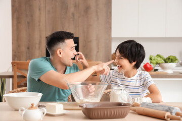 Little boy with his father having fun while cooking in kitchen