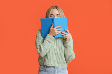 Beautiful young woman with book on red background