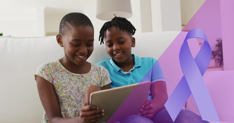 Image of blue ribbon over african american siblings smiling and using tablet