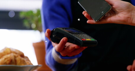Image of currency symbols over caucasian woman paying by smartphone
