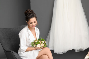 Beautiful young bride with her wedding bouquet sitting in dressing room