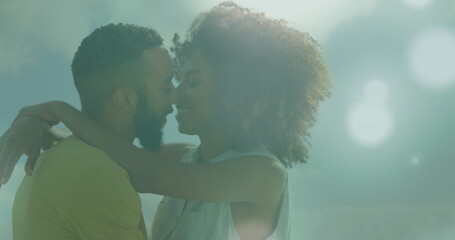 Image of spots of light against african american couple embracing each other
