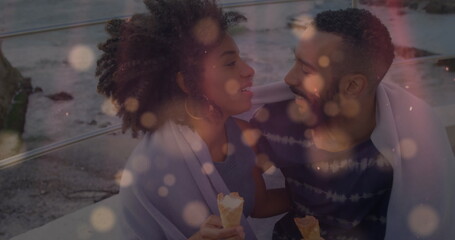 Fototapeta premium Image of yellow spots over african american couple embracing each other at the beach