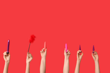 Female hands with different sex toys on red background