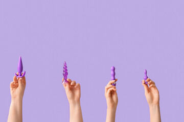 Female hands with anal plugs and vibrator on lilac background