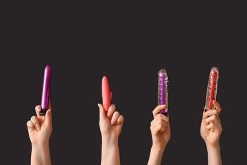 Female hands with different vibrators on dark background