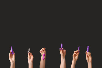Female hands with different sex toys on dark background