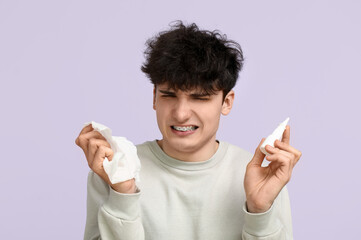 Young man with nasal drops and tissue on color background. Allergy concept