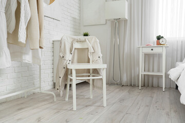 Chair with jacket in light bedroom interior