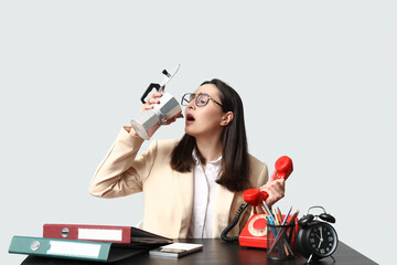 Businesswoman drinking coffee while sitting at table on light background. Concept of overwork and deadline