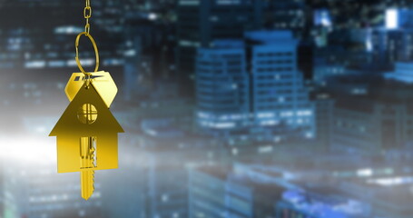 Image of metal house shaped key chain over illuminated buildings in background