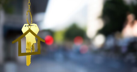 Image of gold house key and fob over out of focus cityscape