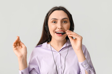 Happy female technical support agent in headset on grey background