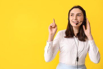 Female technical support agent in headset pointing at something on yellow background