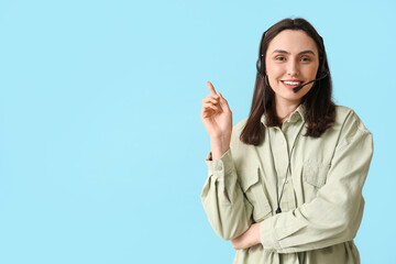 Female technical support agent in headset pointing at something on blue background