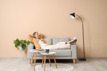 Young woman resting on sofa in beige living room