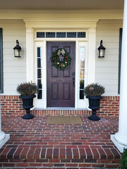 front door to a brick house with a Christmas wreath and a lantern at the entrance.
