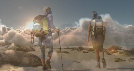 Caucasian couple hiking on rocky beach, carrying backpacks