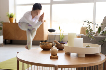 Candles with massage balls and Tibetan bowl on table of sporty woman doing yoga at home, closeup