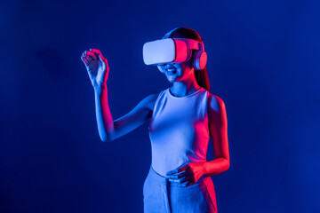 Smart female standing with surrounded by cyberpunk neon light wear VR headset connecting metaverse,...