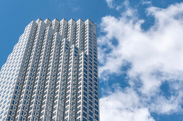 A Skyscraper Against Blue Sky with Fluffy White Clouds