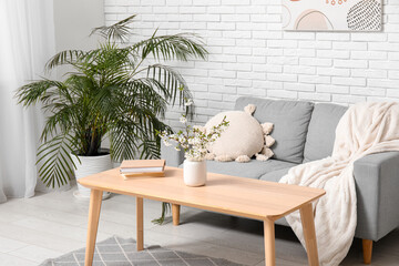 Blooming branches on table in interior of stylish living room