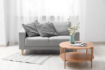 Blue vase with blooming branches on table in stylish living room