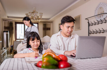 A family of three in the living room painting with their daughter