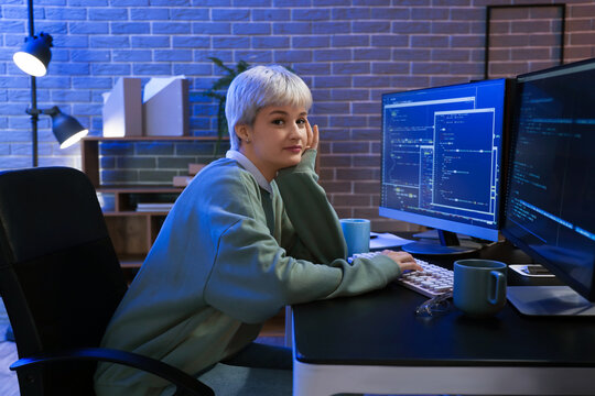 Female programmer working with computer in office at night
