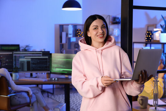 Beautiful programmer with laptop in office at night