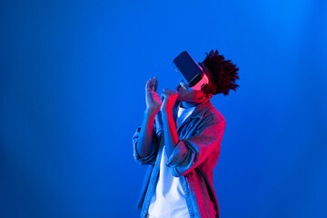 Young African American singer using through VR glasses enjoy singing song with karaoke meta...